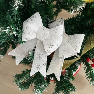 Close-up of white PVC Christmas bow with silver snowflakes on a festive evergreen tree