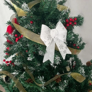Close-up of a white Christmas bow with silver snowflakes on a decorated pine tree