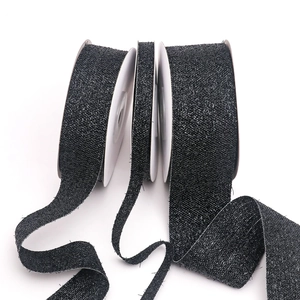 Macro detail of black glitter ribbon with silver metallic thread on white spools
