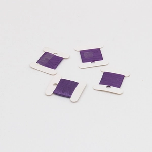 Close-up of four purple sewing thread spools on white holders for DIY handmade crafts