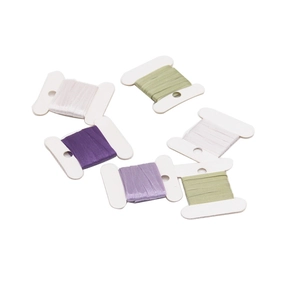 Macro view of six DIY sewing spools with satin ribbons in white, green, and purple