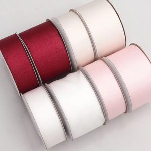 Detailed view of high-gloss silk satin ribbon rolls in wine red, cream, white, and pink