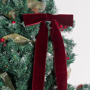 Detail of burgundy velvet Christmas bow on a festive holiday tree with berries
