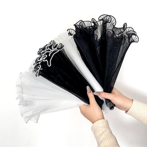 Close-up of pleated mesh cuffs with faux pearl edges in black and white styles