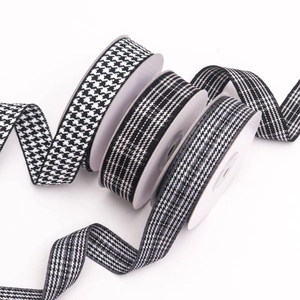 Detailed close-up of houndstooth and striped ribbons on spools for DIY hair accessories
