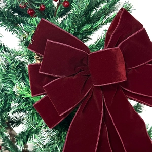 Grand nœud en velours bordeaux avec longs rubans sur une branche de sapin de Noël décoré