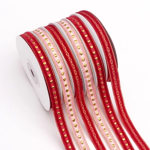 Vista macro de cintas de regalo de terciopelo con corazones dorados en rojo y rosa