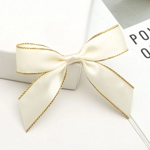 Close-up of cream satin ribbon bow with elegant gold glitter edges for gift wrapping