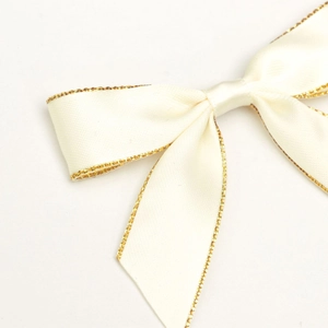Detailed view of cream satin bow with gold metallic edge for gift box packaging
