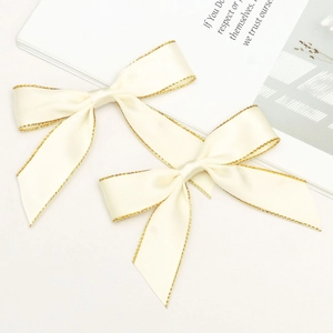 Detail of cream satin bows with gold metallic edges for gift box and cake decoration