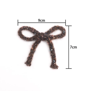 Close-up of handmade 9cm x 7cm crochet bow accessory in mixed brown yarn texture