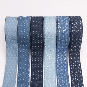 Blue denim ribbons with embroidery and silver sequins on rolls for DIY sewing projects