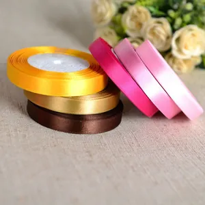 Close-up of 1cm colorful satin polyester ribbon rolls for gift wrapping on rustic fabric