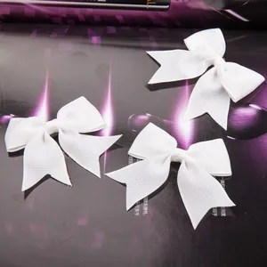 Detailed macro view of white ribbed grosgrain ribbon bows with serrated dovetail edges