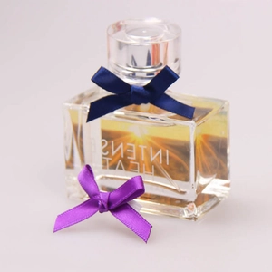 Close-up of a blue satin ribbon bow tied on a glass bottle with golden liquid detail