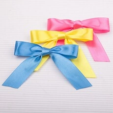 Detail of pink, yellow, and blue satin ribbons with gold edges for gift packaging
