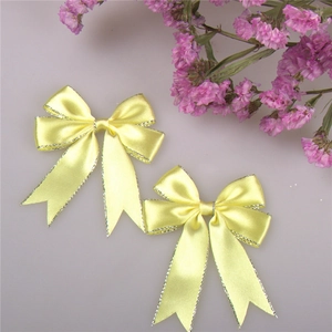 Detail of yellow satin bows with silver edges and swallowtail for gift packaging
