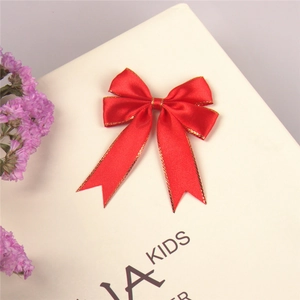 Macro shot of red satin ribbon bow with gold edges and swallowtail ribbons for gift boxes