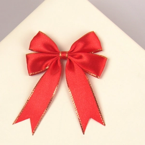 Detail of a red satin ribbon bow with gold glitter edges for gift and cake decoration