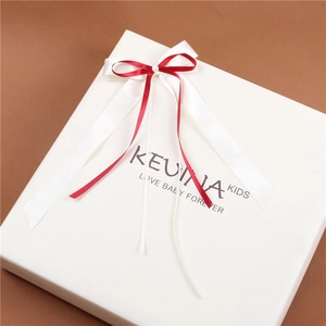 Close-up of a white square gift box featuring a luxury red and white silk ribbon bow