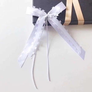 Close-up of a white silk ribbon bow with delicate heart-shaped edge decorations for gift wrap