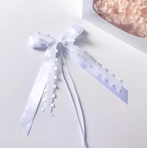 Close-up of white satin ribbon bow with unique heart cutouts for elegant gift wrapping