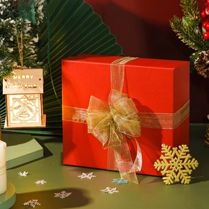 Detail of red gift box with wide golden organza ribbon and elegant bow decoration