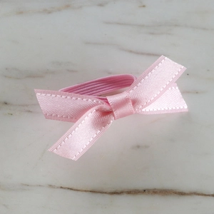 Detailed view of handmade pink ribbon bow tied with fine edge stitching on elastic hair band