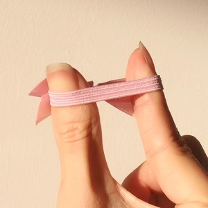 Pink handmade bow hair tie with high elastic band shown being stretched for durability