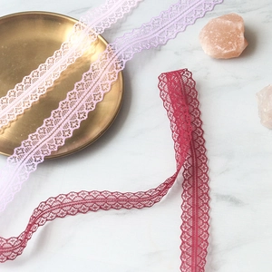 Detail of 3cm wide lace ribbon with floral pattern in purple and burgundy for DIY crafts