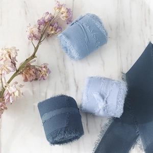 Detailed view of handmade frayed edge chiffon ribbons in three shades of blue on marble surface