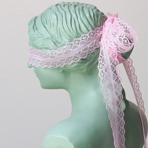 Close-up of pink lace ribbon with floral patterns tied on a sculpture as DIY headwear