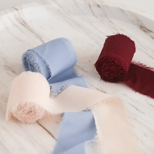 Detail of frayed edge chiffon silk ribbons in burgundy light blue and cream colors