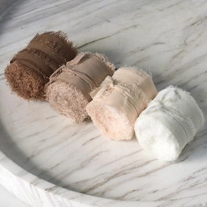 Detail of four-color frayed edge chiffon ribbons on white marble tray for weddings