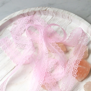 Pink lace ribbon with floral pattern and scalloped edges on marble tray decor