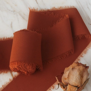 Burnt orange frayed edge chiffon ribbon for bridal bouquets on marble surface