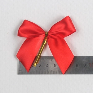Red satin bow with gold wire twist tie on a white textured background for gift wrapping