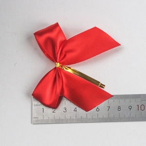 Detail of a red satin ribbon bow with gold twist tie and measuring scale display