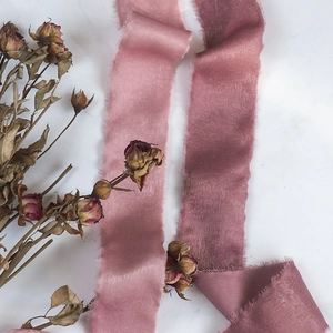 Close-up of velvet flocked ribbon with raw edges in soft pink and deep plum tones
