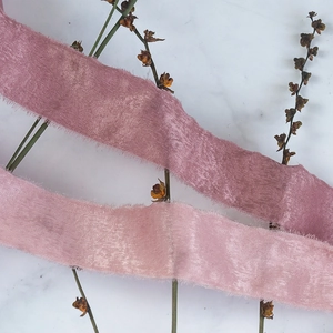 Frayed edge velvet silk ribbons in dusty pink and blush pink on marble surface