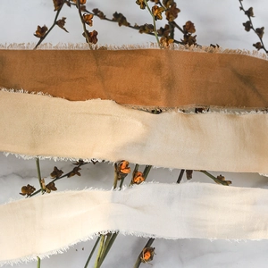 Macro detail of handmade frayed cotton silk ribbons in caramel and cream colors