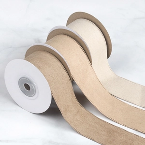Close-up of three rolls of beige linen decorative ribbons with white stitched edges