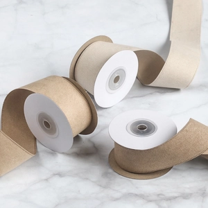 Detail of sand beige velvet ribbon with fine stitched edges on white marble