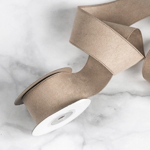 Detailed view of khaki velvet ribbon with reinforced edges on a white spool