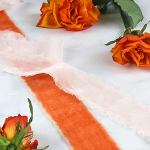 Detail of frayed velvet ribbon in sunset orange and pale pink for wedding gifts