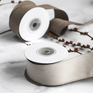 Detail view of brown and beige velvet ribbons with stitched edges on a marble surface
