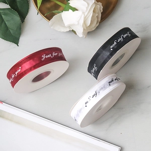 Close-up of 'Just for you' printed ribbons in red black and white on marble background