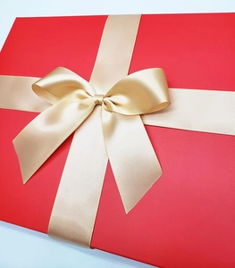 Detail view of a luxury red gift box with a high-quality champagne gold silk ribbon bow