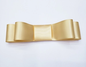 Close-up of handmade double-layered champagne gold satin ribbon bow with smooth finish