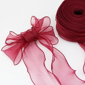Close-up of wine red fishtail chiffon ribbon with delicate wave stitched edges for DIY